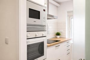 a white kitchen with a microwave and a stove at Apartamento Premium Ávila PLAZA MAYOR con PARKING in Ávila