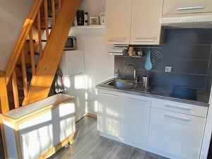 a kitchen with white cabinets and a sink and a staircase at Location duplex ,Station du Seignus d'Allos in Allos