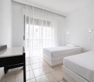 a bedroom with two beds and a desk and a window at Ioli Beach in Skala Fourkas