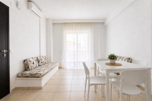 a white living room with a table and a couch at Ioli Beach in Skala Fourkas