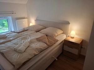 a white bed with two pillows and a night stand at EifelAuszeit in Simmerath