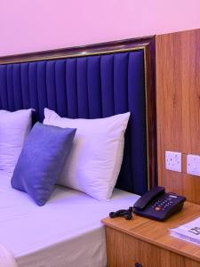 a bed with white pillows and a phone on a desk at FOURTOWERShotel in Ijoko Lemode