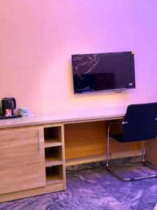 a desk with a television on a pink wall at FOURTOWERShotel in Ijoko Lemode