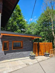 a small house with a wooden fence in front of it at Chatka Bystrá jacuzzi,stars,river in Bystrá