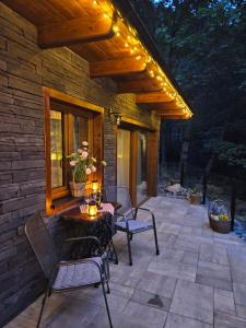 a patio with chairs and a table with lights on it at Chatka Bystrá jacuzzi,stars,river in Bystrá