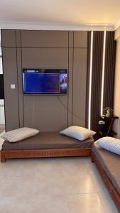 a room with two beds and a tv on the wall at Studio Prestige - 10min de ParkMall in Sétif