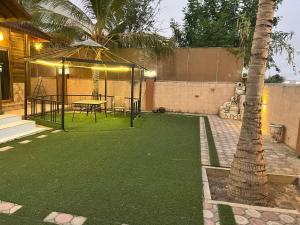 a backyard with a table and a palm tree at شالية الكوخ in Salalah