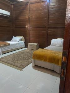 a bedroom with two beds and a wooden wall at شالية الكوخ in Salalah +13 photos