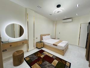 a bedroom with a bed and a mirror and a stool at Neat & Modern Studio 2Mins Pyramids - Royal desert Inn in Cairo