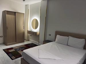 a bedroom with a white bed and a mirror at Neat & Modern Studio 2Mins Pyramids - Royal desert Inn in Cairo