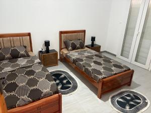 a bedroom with two beds and two rugs at Talia in Bejaïa