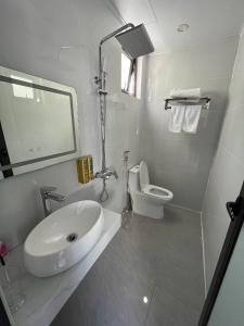a white bathroom with a sink and a toilet at Hải Đảo Homestay in Quan Lạn
