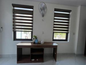 a desk in a room with two windows and a clock at Hải Đảo Homestay in Quan Lạn