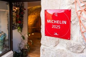 a red sign on the side of a building at La Maison du Passage - Chambres - Suites premium, Spa, Piscine et Restaurant in Martignargues