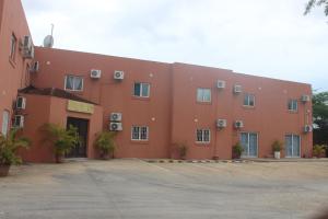 a large orange building with plants in a parking lot at Astória - Hotel & Suites in Soyo