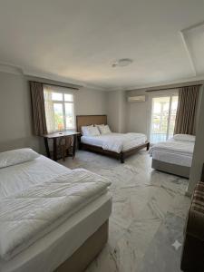 a bedroom with two beds and a desk and two windows at Narçiçeği in Değirmendere