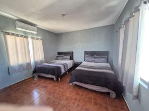 two beds in a room with blue walls at Bugambilias Condo D with Pool and Beach Access - Rancho Bugambilias in San Felipe