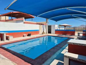 a swimming pool with a blue umbrella over it at Bugambilias Condo D with Pool and Beach Access - Rancho Bugambilias in San Felipe