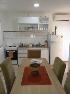 a kitchen with a wooden table and chairs and a kitchen with white appliances at Escalera del éxito Villa Ramallo in Estación Ramallo +5 photos
