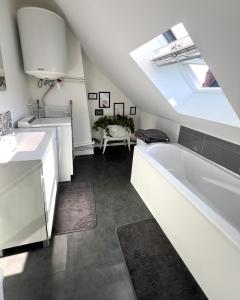 a white bathroom with a tub and a sink at Le petit nid rouennais in Rouen
