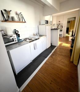 a kitchen with white appliances and a wooden floor at Le petit nid rouennais in Rouen