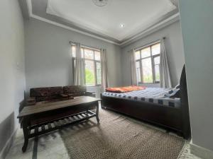 a bedroom with a bed and a couch and windows at The Moonland Homestay in Shalkār