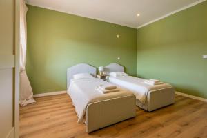 two beds in a room with green walls and wooden floors at Vivenda Verivitor - Saltwater Pool, Garden, BBQ & Tennis Court in Sesimbra +32 photos