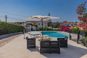 a patio with a table and umbrella next to a pool at Vivenda Verivitor - Saltwater Pool, Garden, BBQ & Tennis Court in Sesimbra