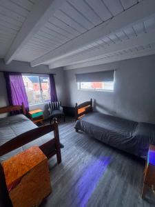 a room with two beds and a couch and windows at El Kamaruco Hostel in El Chalten