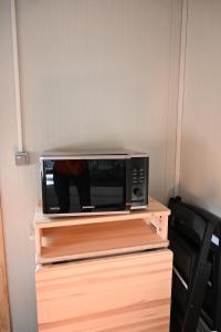 a microwave sitting on top of a wooden shelf at Single room - small cabin - stuga - self check in - Gällivare Koskullskulle in Koskullskulle