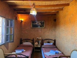 a room with two beds and a table and a window at Riad Espace Asrir Tiznit in Tiznit