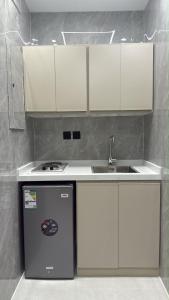 a kitchen with white cabinets and a sink and a refrigerator at شقة سحاب ابها in Abha