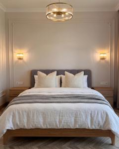 a bedroom with a large bed with white sheets and a chandelier at Lakes Places Villas in Kyiv