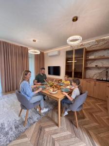a group of people sitting around a wooden table at Lakes Places Villas in Kyiv