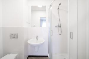 a white bathroom with a sink and a shower at Pokoje Złota Plaża in Międzywodzie