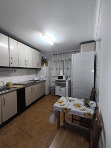 a kitchen with a table and a white refrigerator at Casa la parra in Ardales