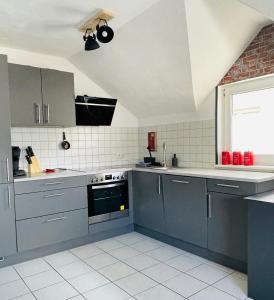 a kitchen with gray cabinets and a white tile floor at LohainsLodge in Burbach