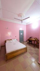 a bedroom with a bed and a pink wall at Hôtel St Jo in Bohicon