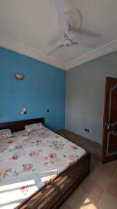 a bedroom with a bed with a blue wall at Hôtel St Jo in Bohicon