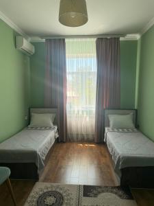 two beds in a room with a window at Sapar de lux hotel in Qyzylorda +1 photo