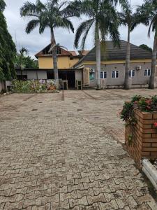 a courtyard with palm trees and a building at GRACECUT HOTEl in Enugu