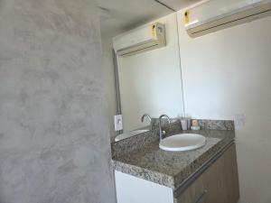 a bathroom with a sink and a mirror at Lindo Duplex na orla de Pajuçara in Maceió