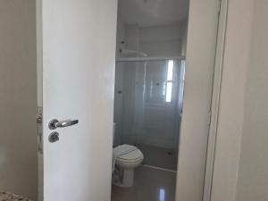 a white bathroom with a toilet and a shower at Lindo Duplex na orla de Pajuçara in Maceió