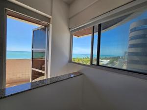 a room with a window with a view of the ocean at Lindo Duplex na orla de Pajuçara in Maceió