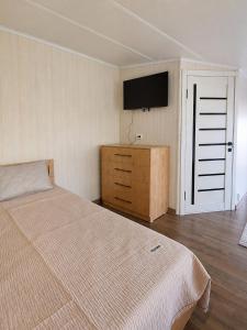 a bedroom with a bed and a tv on the wall at Valentina`s Guesthouse in Korumdy