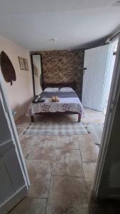 a bedroom with a bed and a brick wall at Kitnetilha in Itamaracá