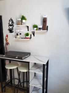 a desk with stools next to a white wall with shelves at Acogedor estudio cerca del aeropuerto in Tijuana