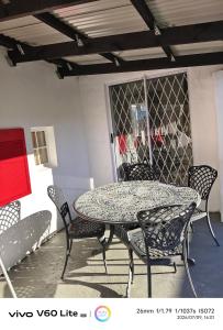 a patio table and chairs with a table and a glass door at Firehouse self-catering cottage 7 in Wellington +7 photos