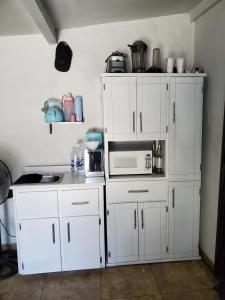 a kitchen with white cabinets and a microwave at Acogedor estudio cerca del aeropuerto in Tijuana