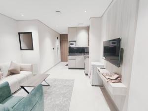 a white living room with a couch and a tv at شقق الإيجار - العروبه in Riyadh